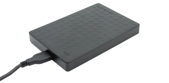 Black Seagate external hard drive connected with a USB cable.