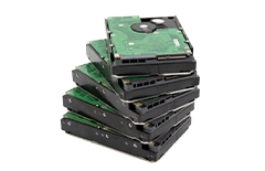 Stack of internal hard drives with exposed circuit boards.